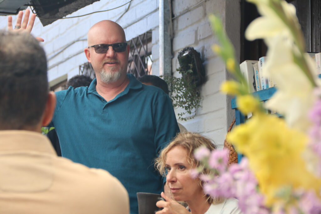 A man raising his hand next to a sitting woman