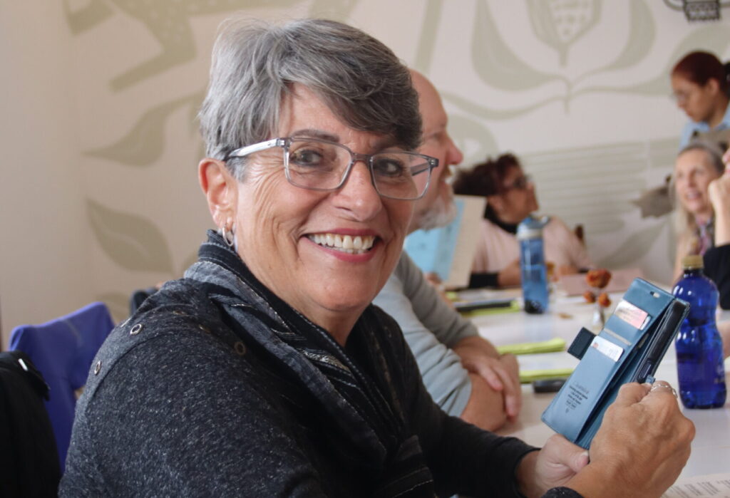 a woman smiling at the camera while holding a phone