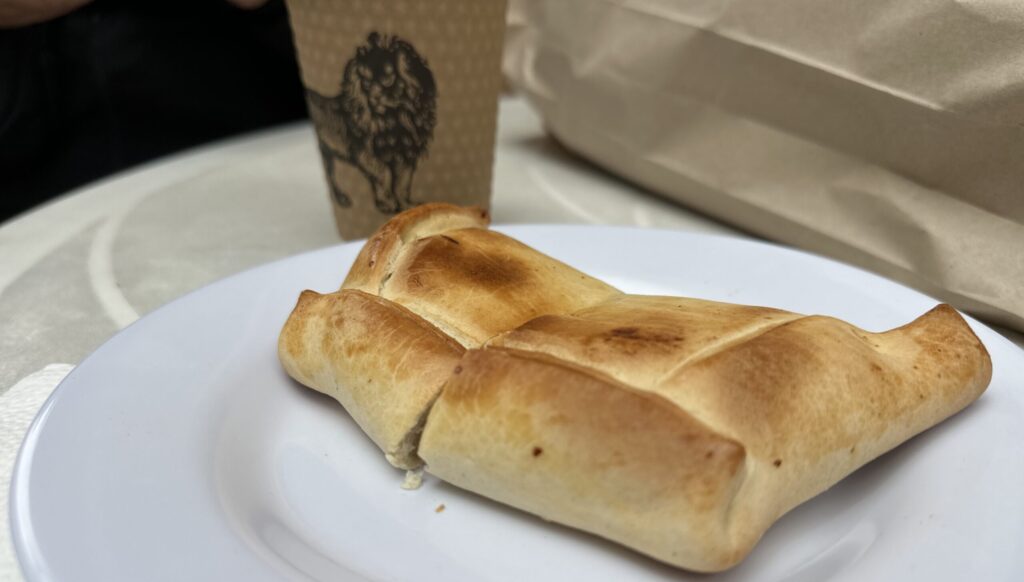 an empanada next to a cup of coffee