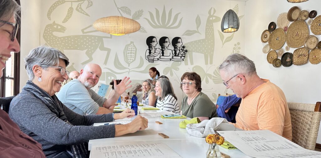 A group of people around a dining table while one man waves