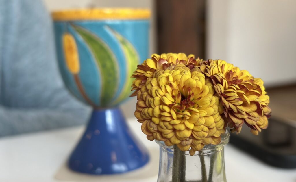 flowers in a small vase in front of a cup
