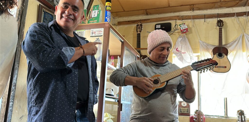 A man pointing at another man playing a balalaika