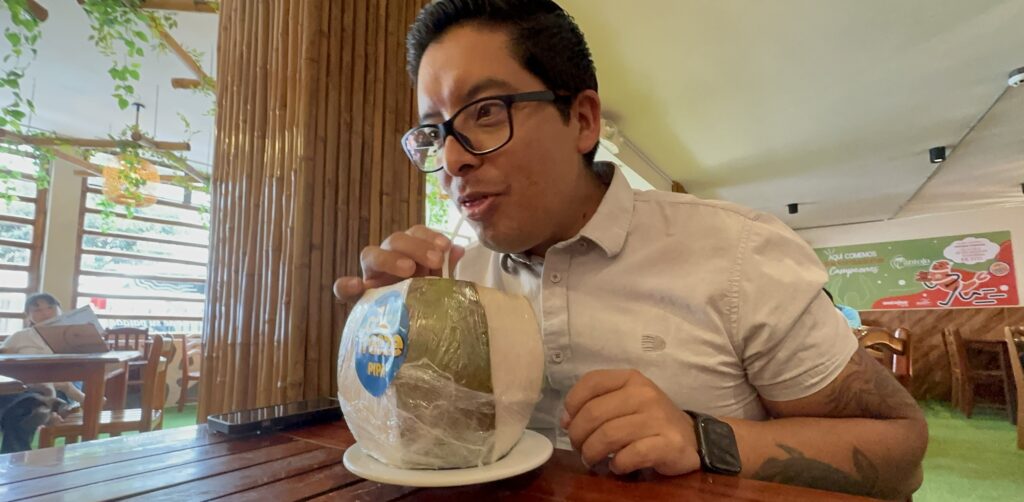 Man drinking from a coconut with a straw in a restaurant
