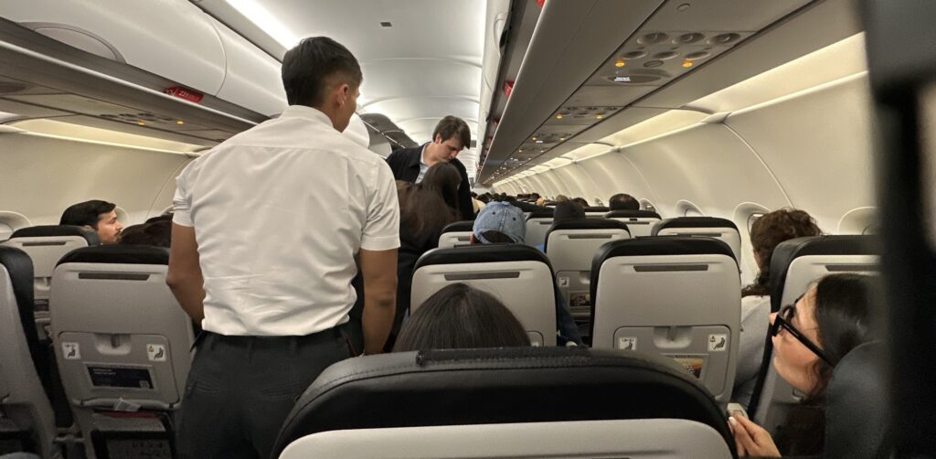 Flight attendant assisting passengers on a plane