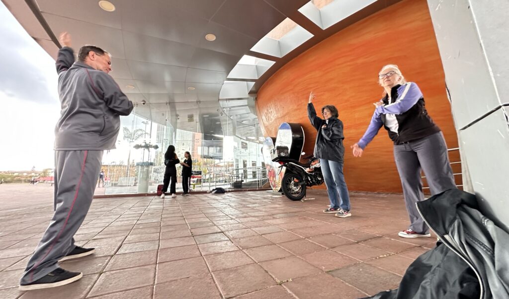 people practicing tai chi under an awning