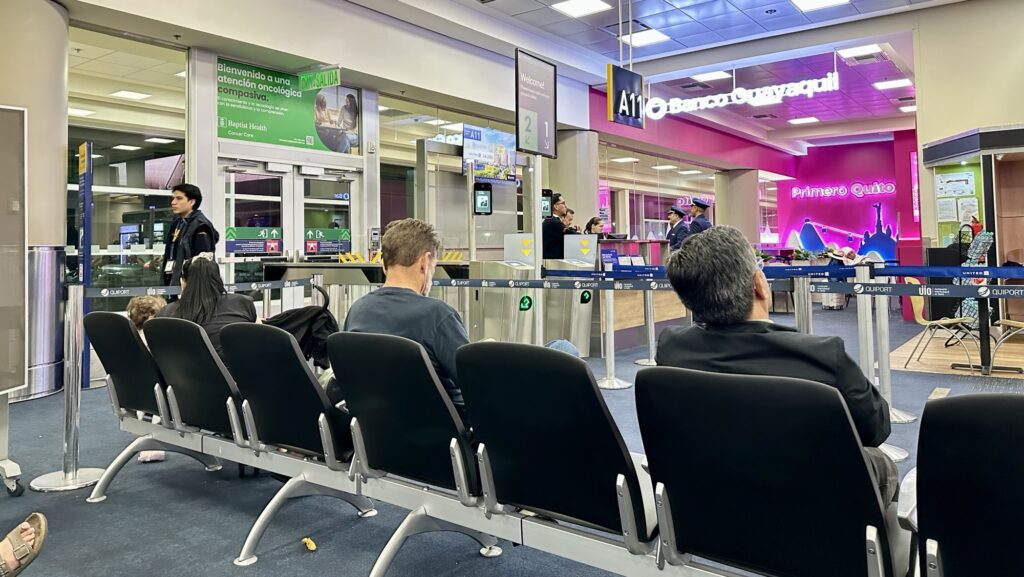 people waiting near an airport gate in Quito