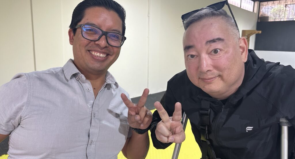 Two men giving peace signs to the camera, one with crutches