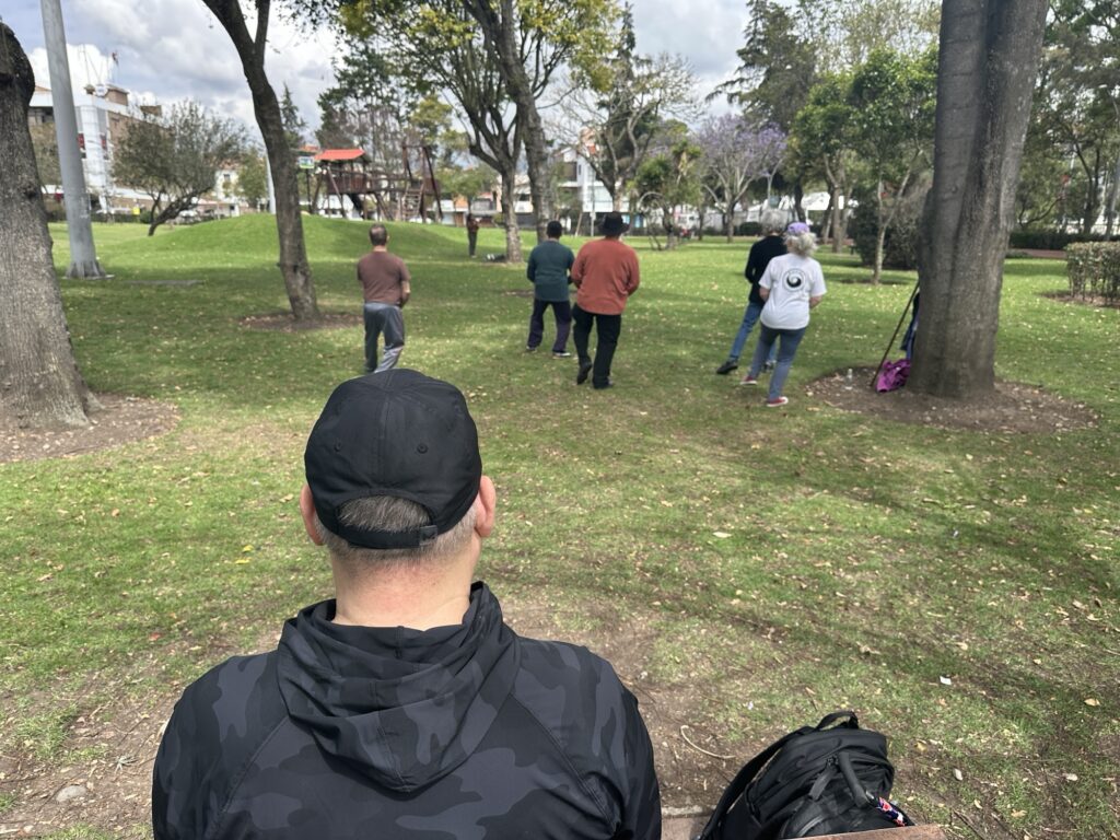 a man sitting at a bench in front of a tai chi class