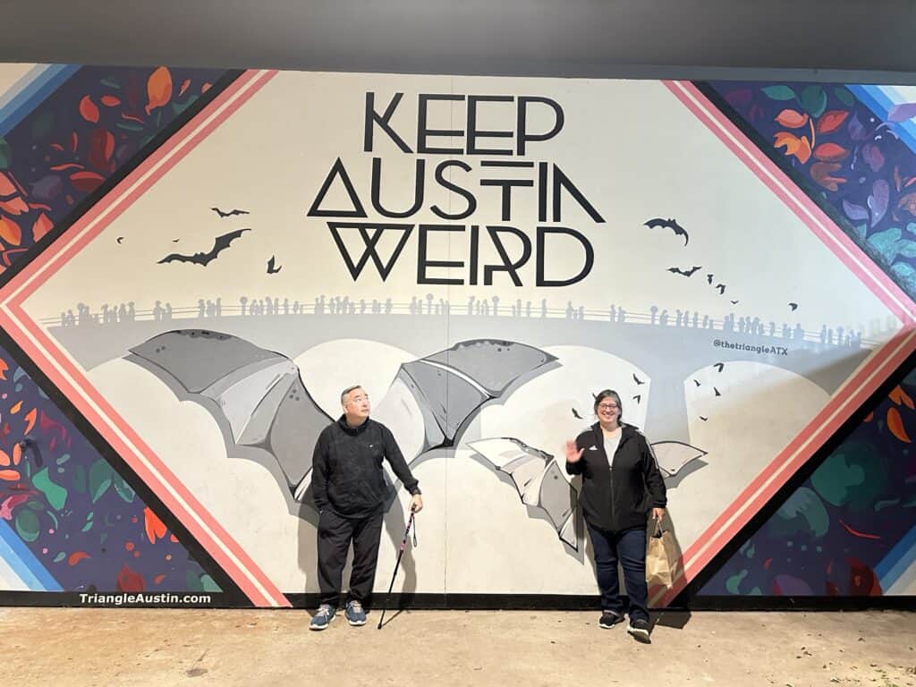 Two people in front of a sign saying Keep Austin Weird