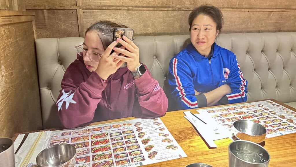 a girl listening to the phone while a woman watches